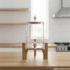 Clear glass water dispenser with wooden stand in modern kitchen