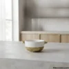 Individual ceramic soup bowl with textured gold base on counter