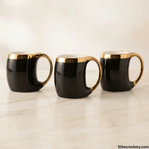 Set of three luxury black ceramic mugs with gold handles on marble counter